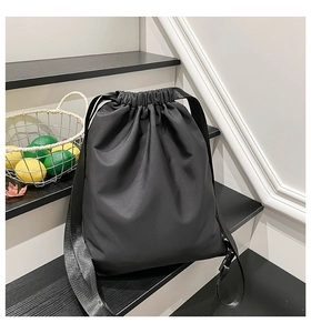 Detail of black drawstring backpack with matte synthetic fabric and wide woven straps