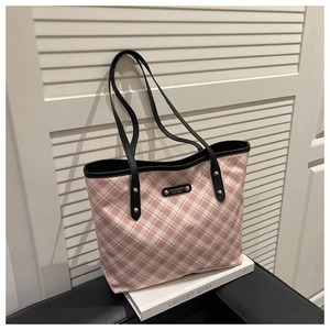 Detail of pink plaid tote bag with black leather straps and golden logo plaque