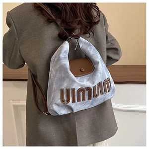 Rear view of a model wearing a light blue denim and brown leather crossbody bag