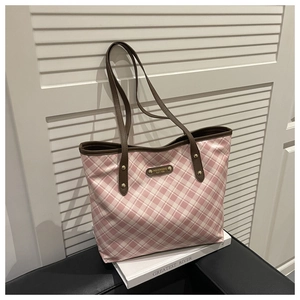 Detail view of pink and white checkered tote bag with brown leather straps and metal rivets