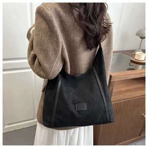 Detail of black suede hobo bag styled with an elegant herringbone blazer and dress