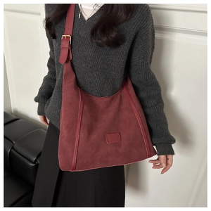 Close-up of wine red faux suede tote bag with golden buckle and sleek leather trim