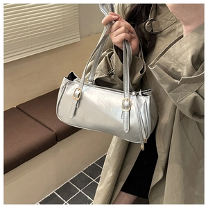 Detail of silver metallic tote bag with glossy finish and elegant golden buckles