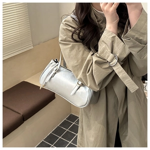 Detail of a silver metallic leather underarm bag with minimalist cylindrical design