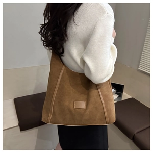Detailed close-up of a large caramel suede tote bag showing soft texture and vertical stitching