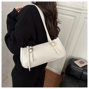 Close-up of a white glossy leather underarm bag with gold buckle on a black sweater
