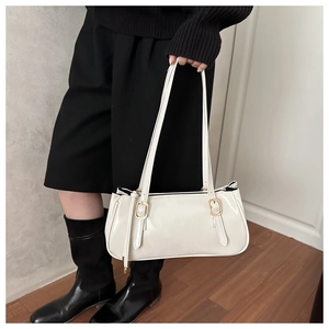 Detail of minimalist cream faux leather handbag with gold buckles and dual shoulder straps