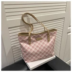 Detail of pink plaid tote bag featuring a golden metal nameplate and khaki leather handles