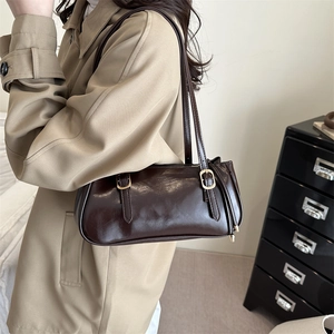 Deep chocolate glossy baguette bag with gold buckles worn over a khaki trench coat