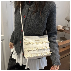Detail of elegant cream lace tote with layered ruffles and metallic brand plaque