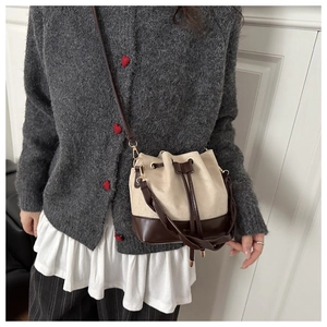 Detail of drawstring bucket bag with leather base and crossbody strap on model