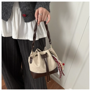 Detail of drawstring bucket bag with braided handle and decorative silk scarf