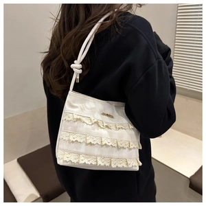 Detail of cream bucket bag featuring layered lace ruffles and checkered texture fabric