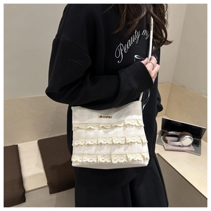 Detailed view of beige plaid shoulder bag with elegant white lace trim and gold logo