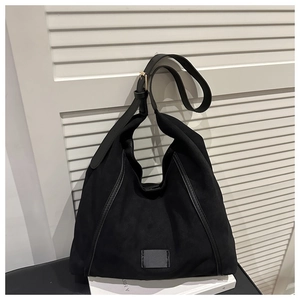 Detail of black canvas tote bag with adjustable shoulder strap and gold metal buckle