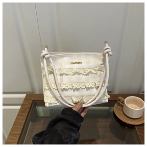 Detail of off-white tote bag with three-layer lace trim and golden logo plaque