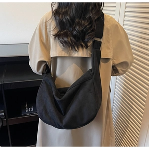 Detail of a black crescent crossbody tote bag showing drape and large capacity on model