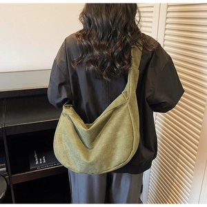 Detailed back view of an olive green crescent crossbody bag with wide strap on a model