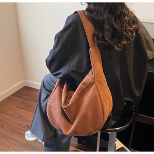 Brown faux suede hobo bag on shoulder showing large capacity and soft drape texture