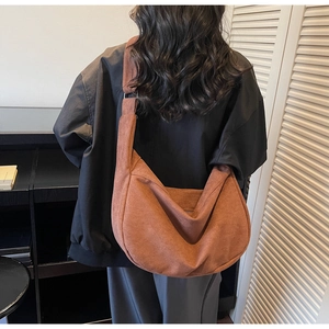 Brown corduroy crescent shoulder bag with wide strap shown from a back view