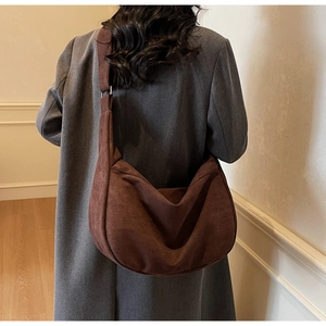 Macro detail of dark brown suede crescent bag showing smooth texture and wide strap