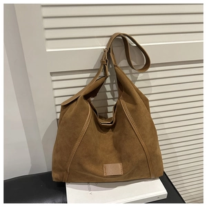 Detail of a brown suede hobo bag with reinforced stitching on the shoulder strap