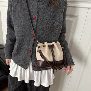 Chic drawstring bucket bag in off-white canvas and dark brown leather on a model