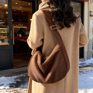 Brown matte suede tote bag with adjustable strap worn over shoulder in winter scene