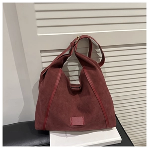 Detailed close-up of burgundy suede hobo bag with contrast leather trim and gold hardware