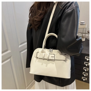 Detalle de bolso bandolera blanco con hebilla plateada y acabado brillante