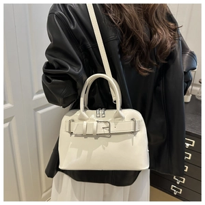 White shell-shaped glossy handbag with decorative belt buckle shown on a model