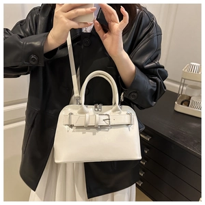 Bolso de mano blanco tipo concha con hebilla metálica llevado por modelo con chaqueta de cuero