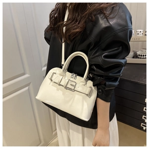 Detalle de bolso blanco de mano con hebilla decorativa y acabado en piel brillante