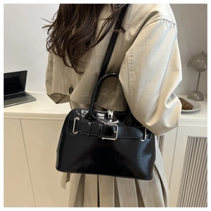 Detalle de un bolso de charol negro con hebilla sobre un escritorio en una oficina moderna