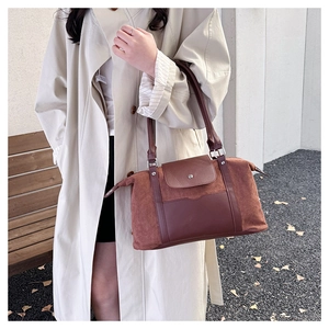 Detail of a large brown retro travel tote bag held by a model in an autumn outdoor setting