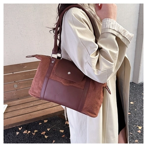 Detail of red-brown suede and leather tote bag shown on a model in autumn setting