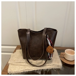 Détail du sac cabas en cuir marron foncé avec charme chien peluche sur couverture