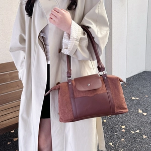 Large brown suede travel bag with shoulder strap shown in a natural outdoor street setting