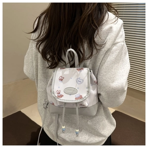 Detail eines kleinen cremefarbenen Rucksacks mit Comic-Prints und Kordelzugverschluss