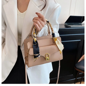 Detail of beige leather crossbody bag featuring gold twist lock and printed silk scarf handle