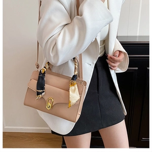 Detail of apricot matte leather bag with gold oval clasp and decorative silk scarf wrap
