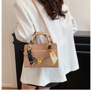 Detailed view of apricot leather square bag with decorative silk scarf on handle