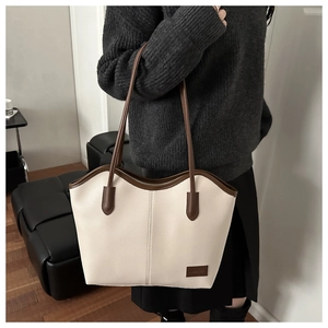 Detail of cream tote bag with brown leather trim and fine stitching on lychee faux leather