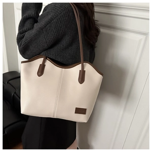Detail of minimalist cream faux leather tote bag with brown straps and litchi texture
