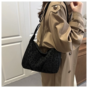 Detail of black leopard print hobo bag with adjustable strap worn with a khaki trench coat