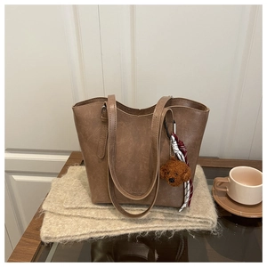 Détail d'un cabas vintage marron avec breloque ours en peluche et texture de cuir souple