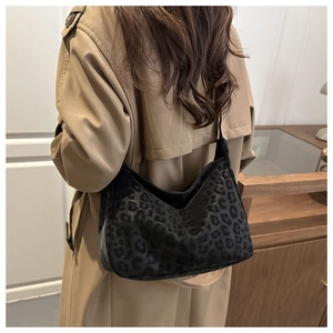 Detail of a large leopard print hobo bag worn with a khaki trench coat in home setting