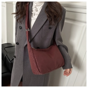 Burgundy hobo shoulder bag with adjustable strap worn with a grey wool coat