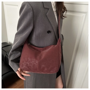 Detail of dark red leopard print tote bag with matte texture on grey blazer