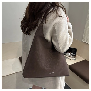 Dettaglio borsa tote in pelle marrone scuro con logo FASHION su cappotto beige